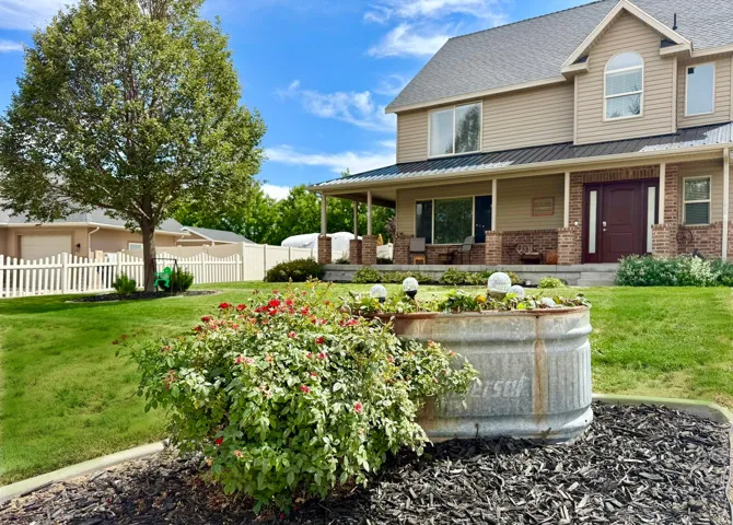 Two-story residence featuring a covered front porch with brick pillars, a dual-panel entry door, and a metal roof accent