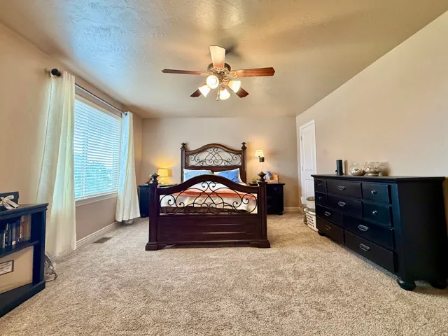 Broadloom carpeting, ceiling fan with integrated lighting, and a window with blinds