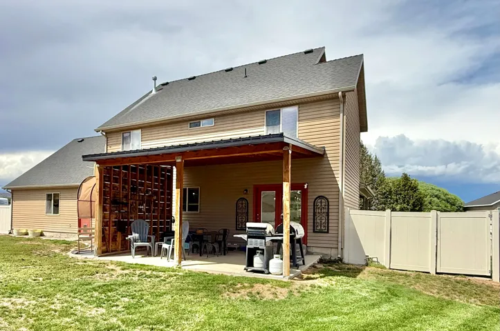 Rear exterior featuring horizontal siding, a covered patio with a wood slatted accent wall, a concrete patio, and a privacy fence