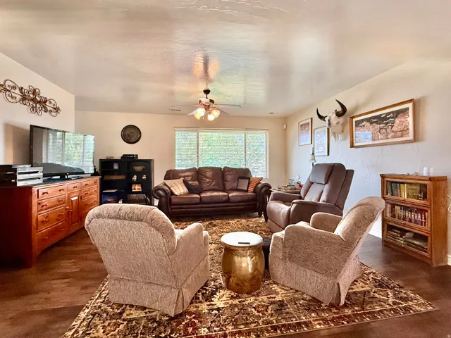 Spacious living area featuring wood-finish flooring, ample wall space, and large windows providing natural light