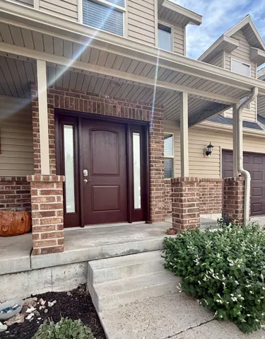 Front entry with a portico, brick accents, and a paneled entry door with sidelights