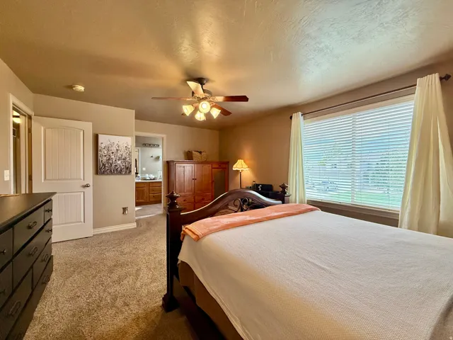 Carpeted room featuring a ceiling fan with integrated lighting, a spacious window with blinds, and a white paneled door