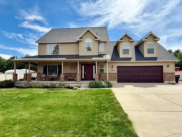Two-story residence featuring a covered front porch with brick pillars, a dual garage, and a concrete driveway.