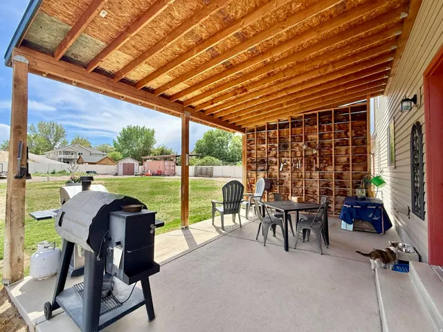 Covered patio with exposed wood ceiling beams and a concrete surface