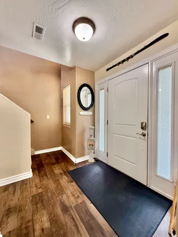 Entryway featuring wood-finish flooring, a white paneled entry door, and a flush mount ceiling light
