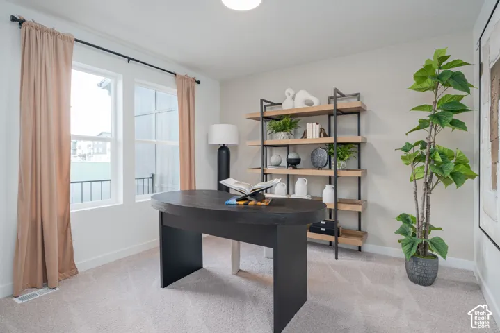 Light-toned wall paint, twin windows, light-colored carpeting, and a built-in shelving unit with a metal frame and wood-finish shelves