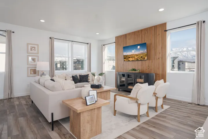 Wood-finish flooring, recessed lighting, multiple windows, and a built-in wood slat accent wall