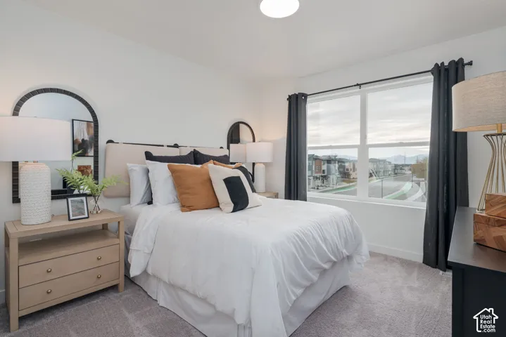 Bright room with a large window, neutral carpeting, and a light-colored headboard