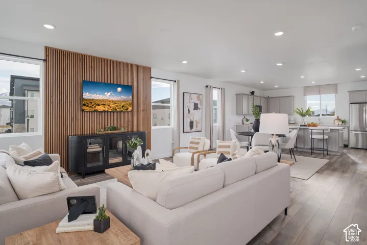 Open-concept living space featuring wood-finish flooring, recessed lighting, and a slatted accent wall