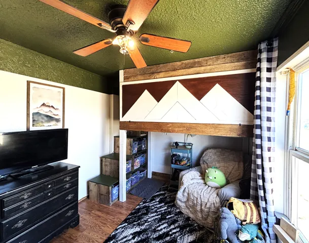 Hardwood-style flooring extends throughout, complemented by a ceiling fan with integrated lighting