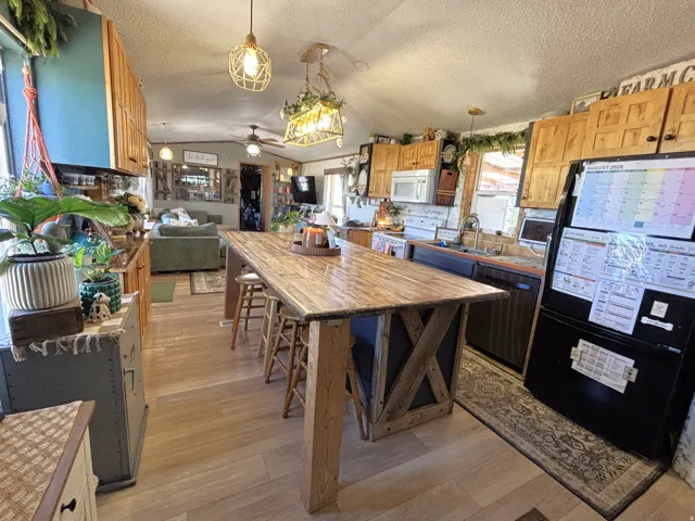 Open-concept kitchen featuring wood-finish flooring, a large custom island, wood cabinetry, and stainless steel appliances