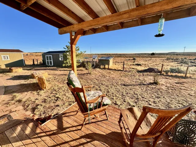 Covered wooden deck with a metal roof, overlooking a vast desert landscape