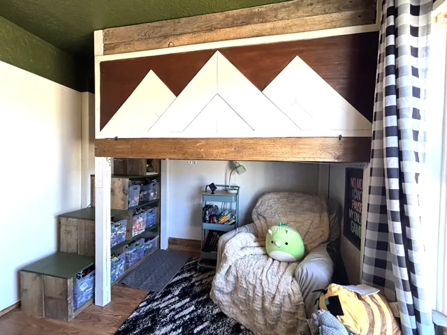 Built-in loft bed with custom wood-finish paneling and mountain motif