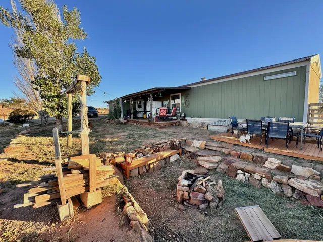 Expansive outdoor area featuring a built-in fire pit, multiple wood decks, and a covered patio