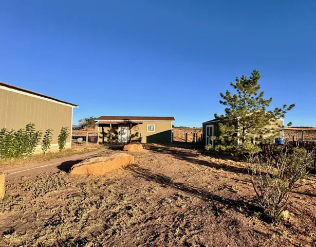 Exterior property featuring three distinct structures with horizontal siding and a clear sky backdrop