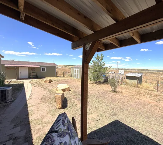 Covered patio with exposed wood beams and a corrugated metal roof