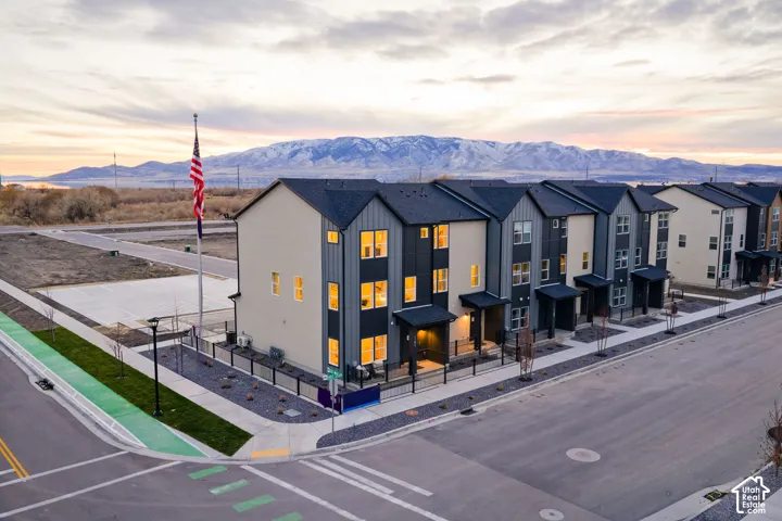 Modern multi-story townhomes featuring contrasting facade materials, individual entryways, and well-lit interiors