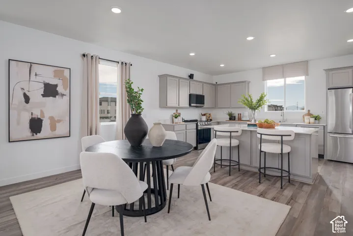 Recessed lighting, wood-finish flooring, white walls, gray cabinetry, and stainless steel appliances