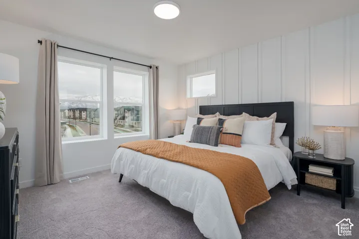 Plush carpeting, multiple windows providing natural illumination, and a feature wall with vertical paneling