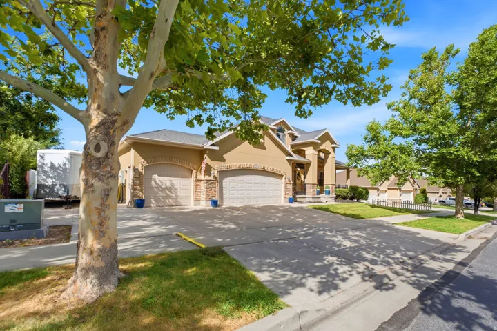 Stucco exterior with stone accents, arched garage doors, a covered entry, and a multi-level roofline