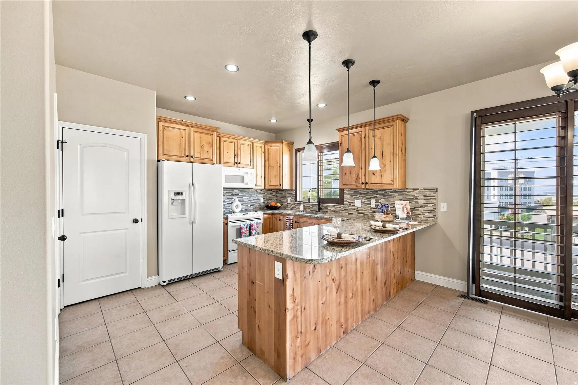 Kitchen featuring tile flooring, wood cabinetry, stone countertops, a tile backsplash, and a sliding glass door with shutters
