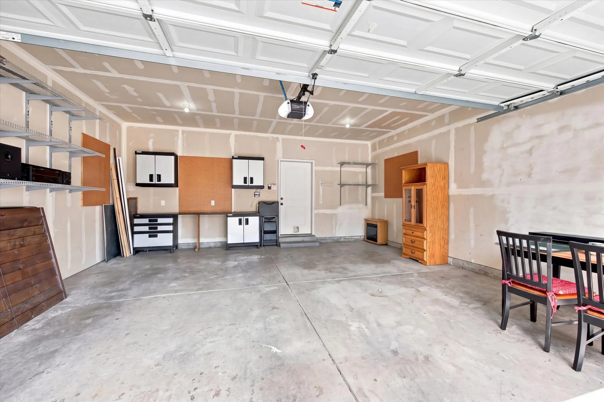 Spacious garage with concrete flooring, overhead garage door, and interior access door