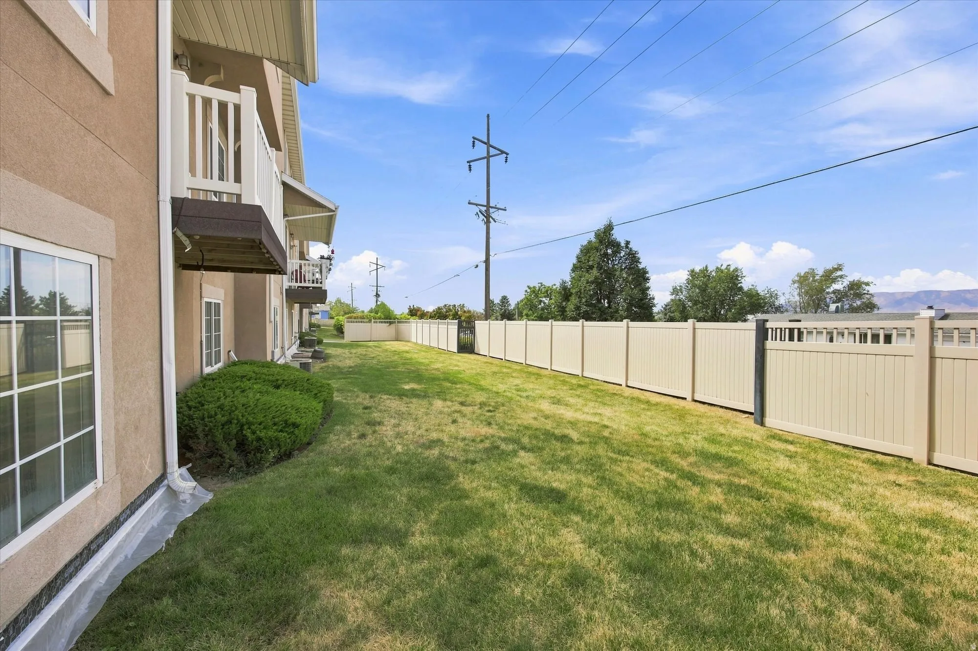 Expansive grassy area with a light-toned privacy fence