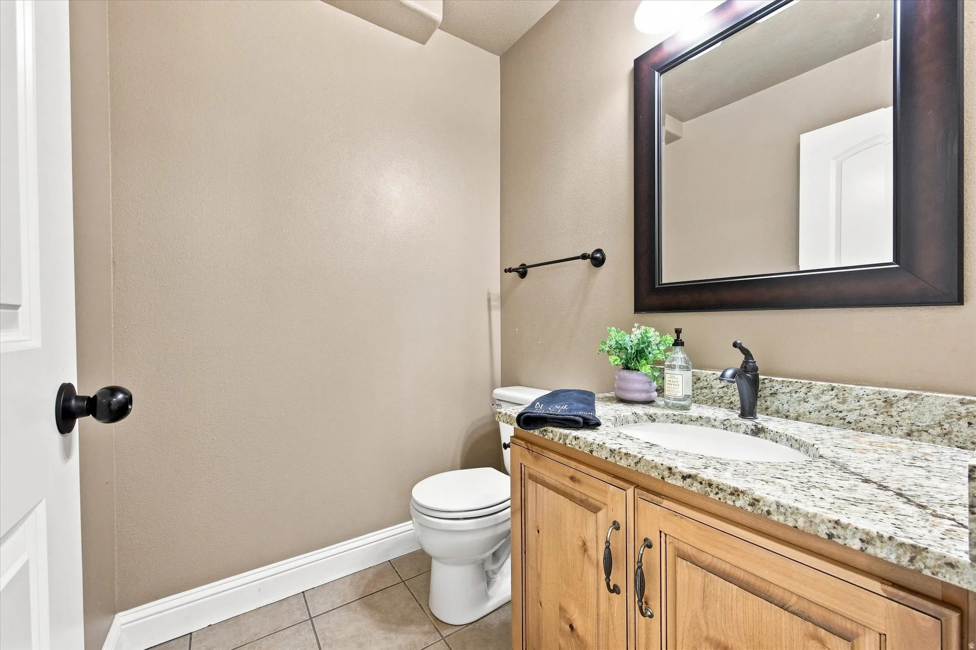 Vanity with granite-style countertop, undermount sink, and dark bronze faucet