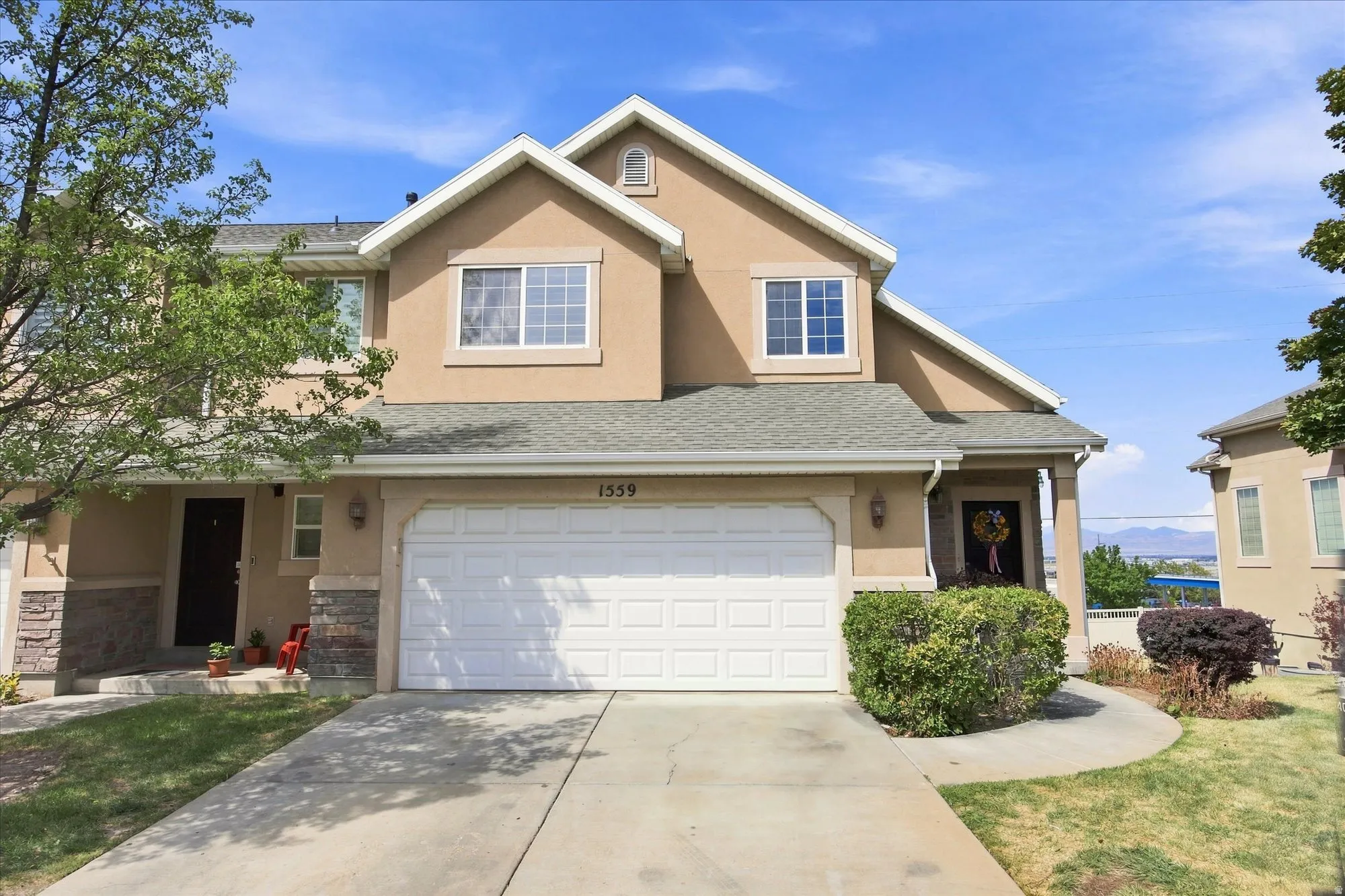 Stucco exterior featuring stacked stone accents, two-car garage, and concrete driveway