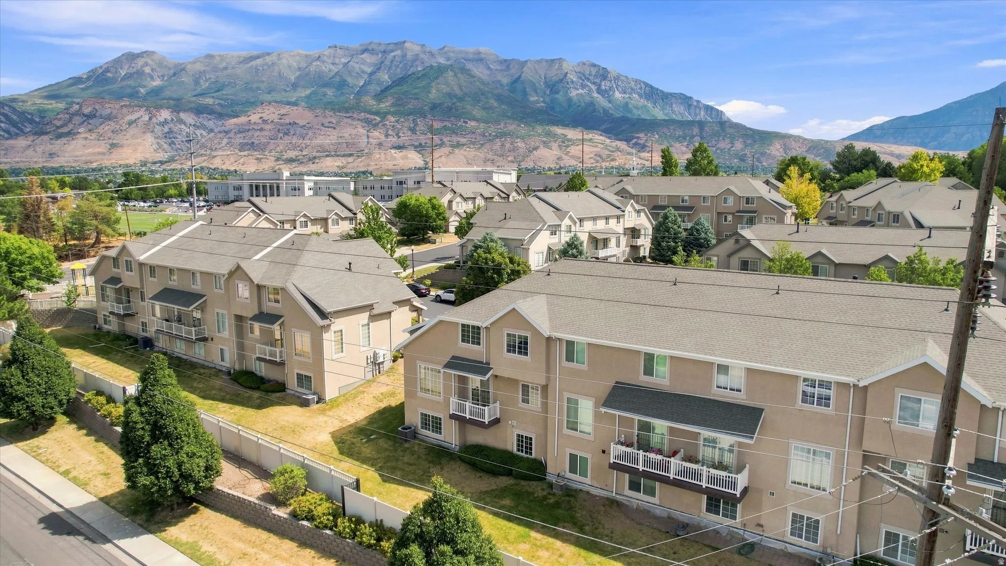 Residential community with multi-level buildings, individual balconies, and a mountain backdrop