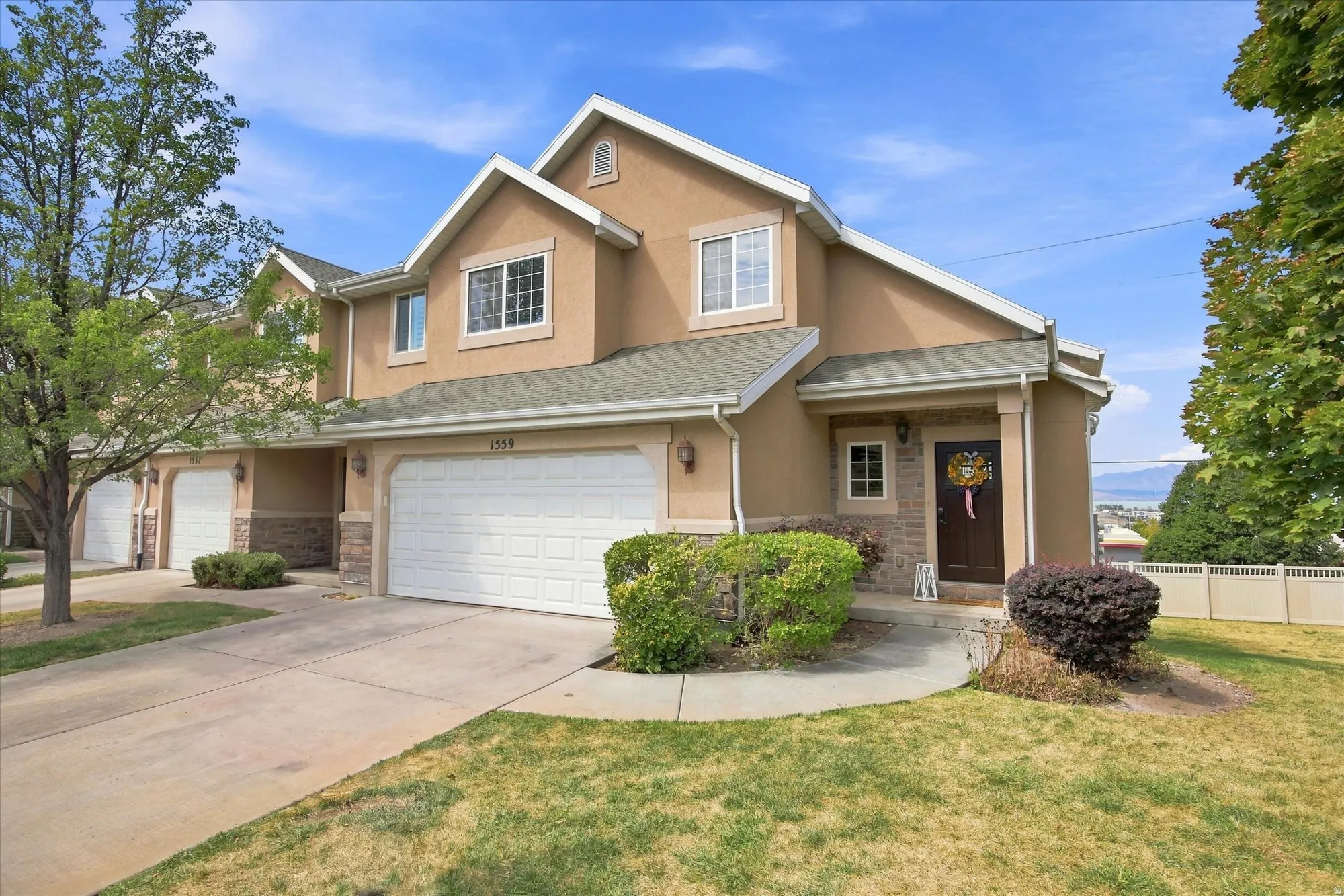 Two-story stucco exterior featuring stone accents, a covered front entry, and an attached two-car garage