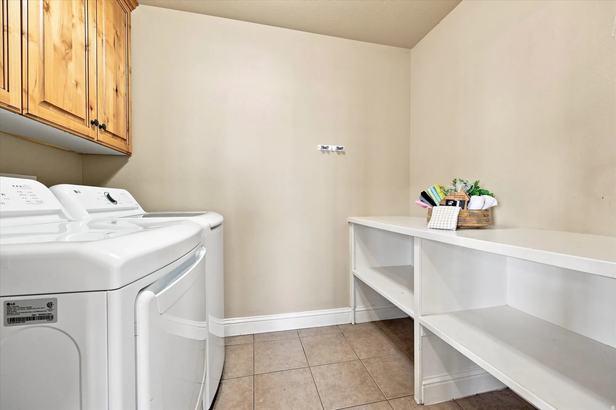 Laundry area featuring tile flooring, built-in wooden cabinetry, and a white built-in storage shelf