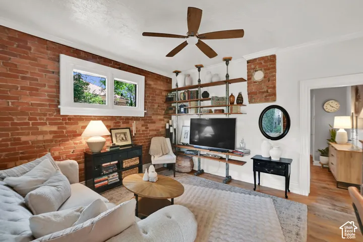 Exposed brick wall, white trim window, wood-finish ceiling fan, built-in shelving, wood-finish flooring