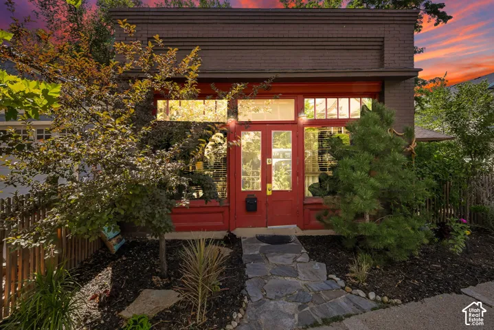 Brick facade with decorative cornice, red double entry doors, transom window, and stone pathway