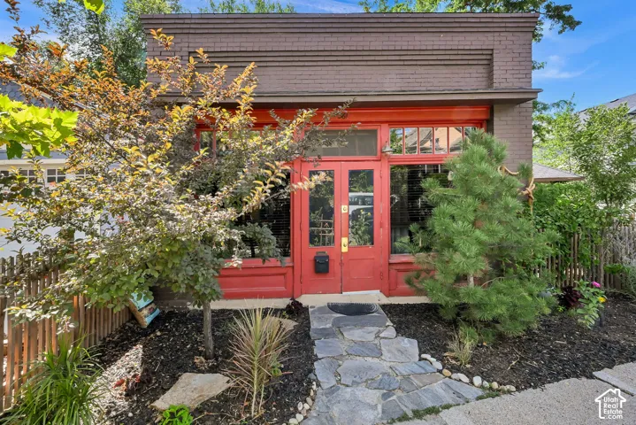 Brick facade with decorative banding, red double-door entry, transom window, and large front windows