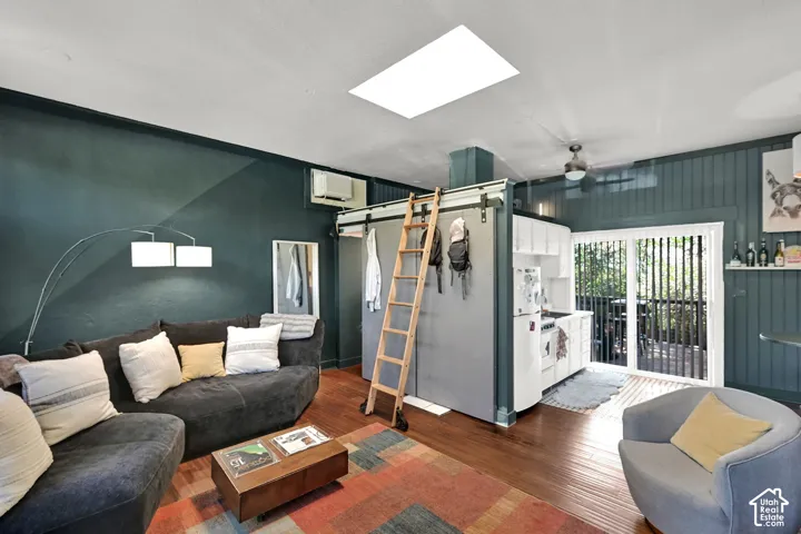 Hardwood-style flooring, white ceiling, skylight, ceiling fan, and sliding glass door to exterior balcony