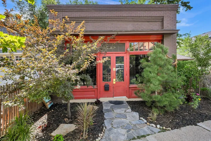 Brick facade with decorative banding, red double-door entry, transom window, and large front windows