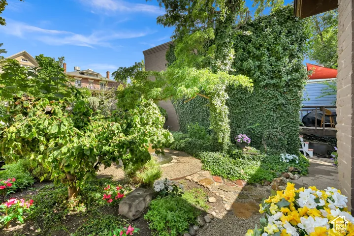 Manicured landscaping with mature trees, a stone pathway, and vibrant floral plantings