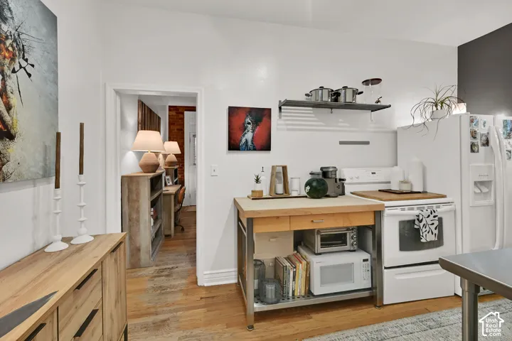Kitchen with white appliances, open shelving, and wood-finish flooring