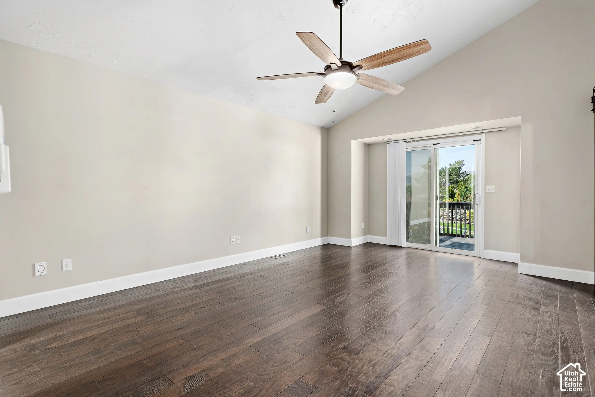 Primary bedroom, vaulted ceilings with a ceiling fan, hardwood flooring, and sliding glass doors leading to a balcony