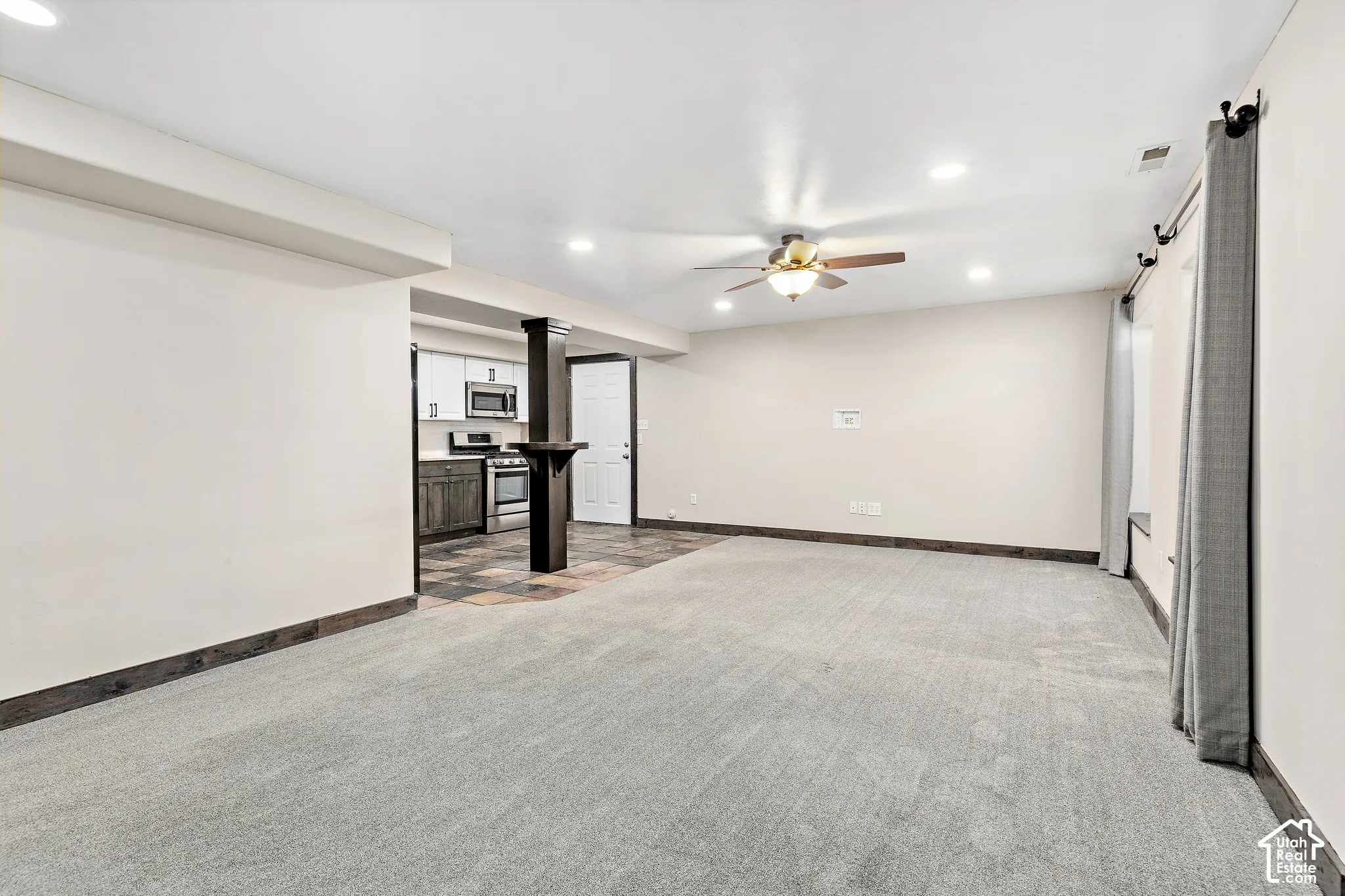 FLEX LIVING basement living room, recessed lighting, ceiling fan, carpeting, wood-finish flooring, and a partial kitchen featuring a stainless steel range
