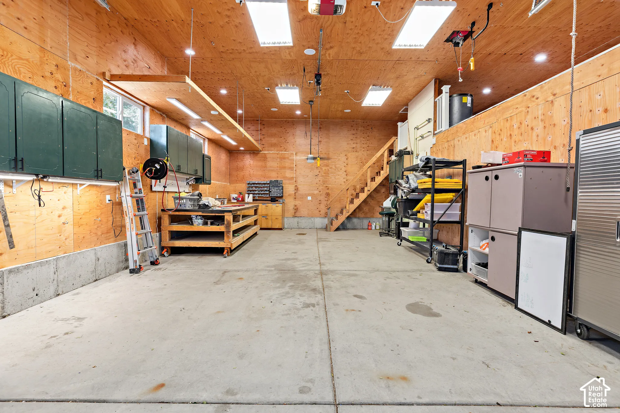 Heated RV garage expansive concrete floor, plywood-paneled walls and ceiling, built-in cabinetry, and integrated overhead lighting