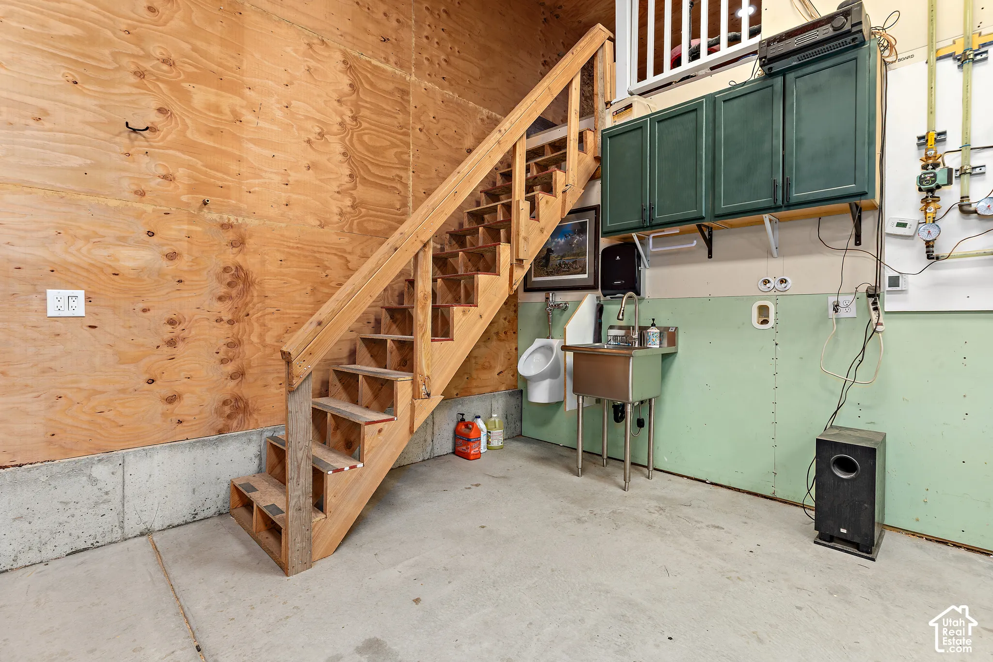 RV garage stairs to mezzanine storage, controls for boiler heating system (boiler heating system is a much more economical way to heat a space this large), stainless steel utility sink, and wall-mounted cabinetry