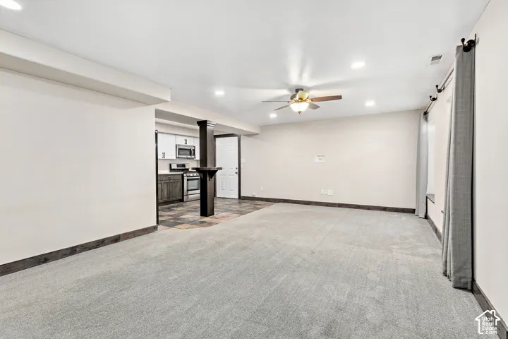 FLEX LIVING basement living room, recessed lighting, ceiling fan, carpeting, wood-finish flooring, and a partial kitchen featuring a stainless steel range