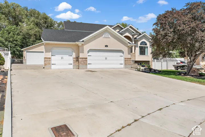 Stucco exterior with stone veneer accents, multiple garage bays, arched window feature