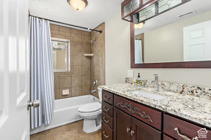 FLEX LIVING basement bathroom featuring a wood-finish vanity with an integrated sink and granite countertop, a framed mirror, and a tiled shower-tub combination with a window