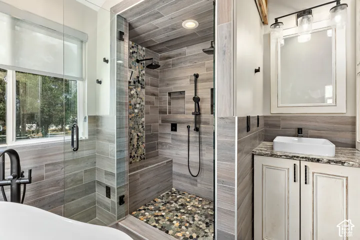 Primary walk-in shower/steam sauna with natural pebble flooring, built-in bench, and black fixtures