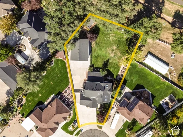 Aerial perspective of the lot featuring a sprawling lawn, mature trees, a detached heated RV garage, and a concrete driveway