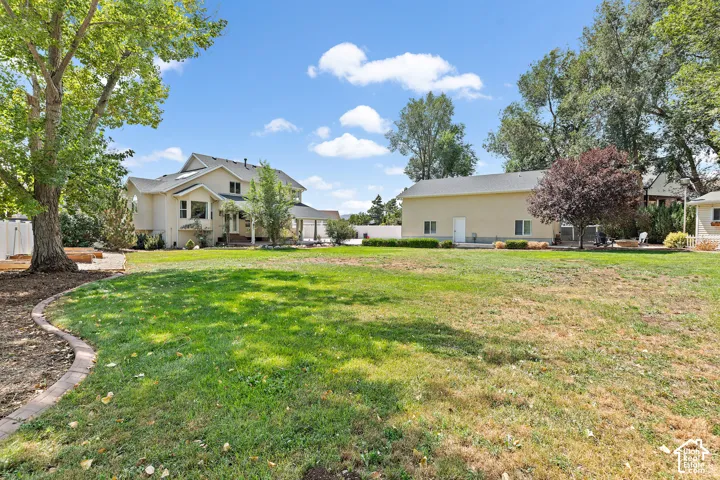 Expansive grass lawn with a defined landscape border, mature trees, and a detached auxiliary building