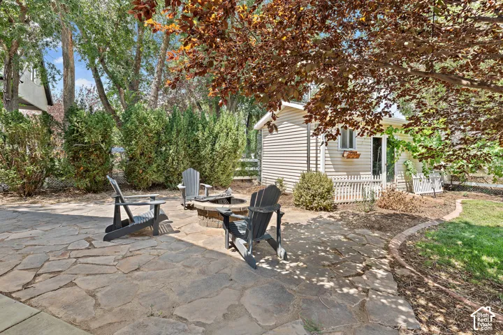 Flagstone patio with a built-in fire pit, surrounded by mature trees and shrubs and landscaping shed